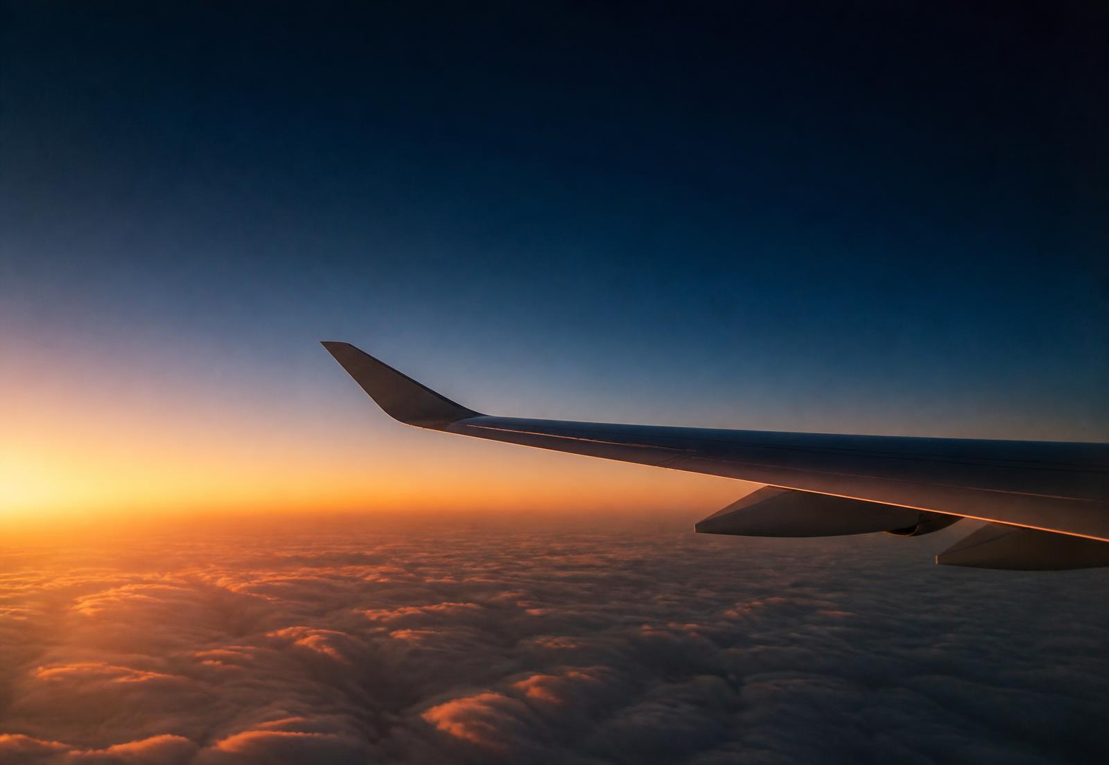 Aircraft wing above golden-hour clouds